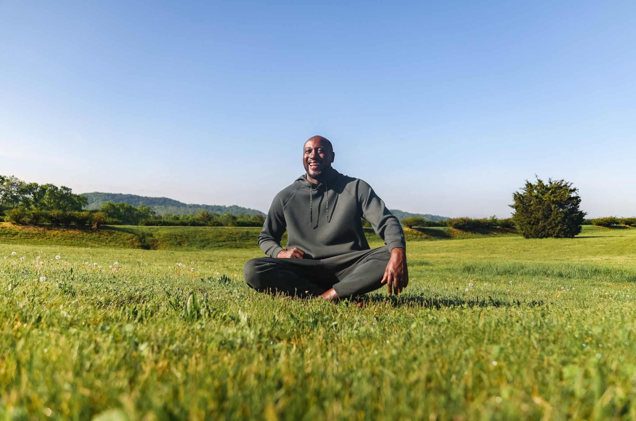 Darryll Stinson sitting crosslegged in a field.