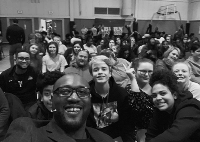 Darryll Stinson smiling with a large crowd after a speaking event