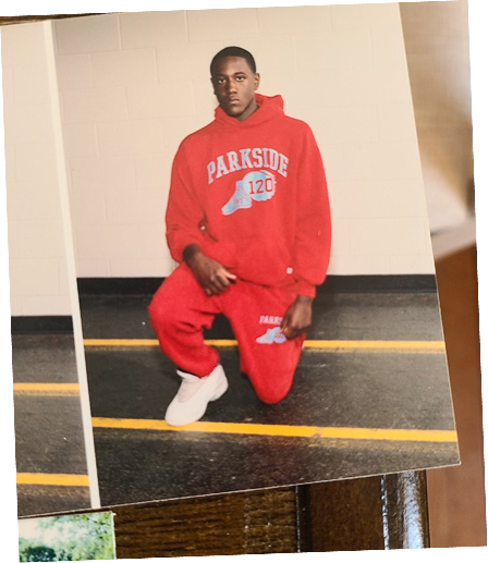 Teenage Darryll Stinson kneeling indoors wearing a red Parkside tracksuit