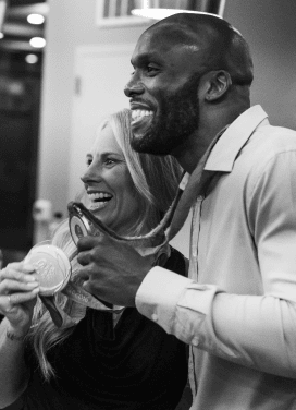 Darryll Stinson smiling with a woman holding a medal at an event.