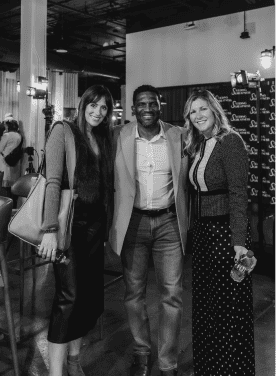 Darryll Stinson with two women at a social event, smiling and dressed professionally.
